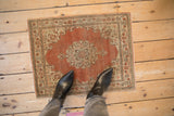 Small distressed antique Tabriz rug in rust orange and ivory, styled underfoot for scale.