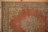 Corner of an antique Tabriz rug with an ivory-brown border and distressed rust-orange field.