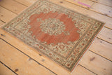 Angled view of a distressed Persian Tabriz rug showing faded rust-orange and ivory tones.