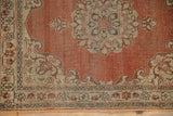 Distressed texture on the corner of an antique Tabriz rug with rust, saffron, and brown motifs.
