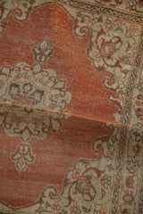 A soft fold reveals the distressed texture and hand-knotted pile of the antique Persian rug.