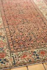 Detailed antique Farahan Sarouk rug border featuring serrated leaves, lotus flowers in faded red and blue.