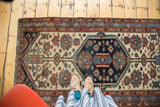 Distressed Hamadan rug's indigo hexagonal medallion, teal, terra cotta, and ivory florals.