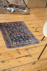 Distressed antique Lilihan rug corner shows navy field with geometric motifs and soft fringe.