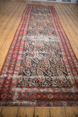 Heavily distressed texture of the antique Malayer runner's dark blue field with paisley and red accents.