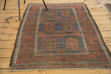Distressed Belouch rug corner: tribal pattern, rich crimson red and cobalt blue.