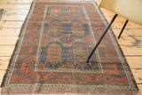 Lower corner of the distressed antique Belouch rug, with ivory zig-zag border and fringe.