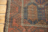 Distressed antique Belouch rug's secured side edge, with cobalt blue geometric patterns.