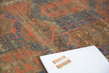 Distressed antique Belouch rug pile, showcasing cobalt blue, crimson, and ivory tones.