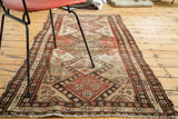 Distressed antique Malayer runner edge with salmon, ivory, and walnut brown animal motifs.
