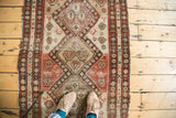 Distressed Malayer runner showing geometric diamonds, tribal animal motifs, salmon, brown, ivory tones.