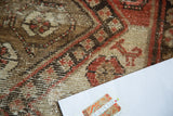 Distressed Malayer rug pile shows abstract animal motifs in brown, ivory, and salmon.