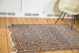 Antique Malayer rug's distressed indigo field with allover herati and faded terra cotta patterns.