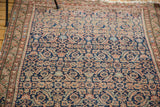 Distressed antique Malayer rug, herati motif with textured indigo, faded terra cotta, and hints of green.