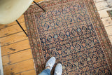 Distressed antique Malayer rug showing faded indigo herati motif and blush terracotta tones underfoot.
