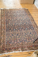 Antique Malayer rug corner showing aged fringe, terra cotta border, and indigo herati motif.