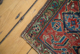 Corner view of antique Persian rug with emerald green stylized samovar/turtle border and rich herati motifs.