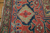 Close-up of the antique Northwest Persian rug's hand-knotted Herati motif in saturated red, deep blue, and sage green.