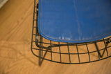 Vibrant blue seat pad with reddish stitching and black wire frame.
