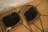 Underside of a black wire Harry Bertoia child chair with blue seat pad.