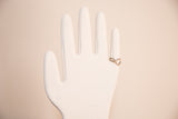 Vintage white glove mold displaying a gold-toned ring on its finger.