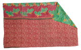Hand-stitched Kantha quilt with red small florals, corner folded to reveal green floral reverse.