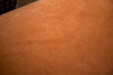 Vibrant tangerine orange velvet upholstery texture on the vintage sofa.