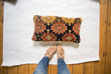 Hand-knotted antique rug fragment pillow, featuring geometric patterns in gold abrash, black, and rust.