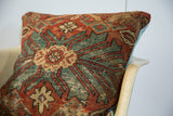 Antique Persian rug pillow corner with aged terracotta, aqua geometric pattern, and blue backing.