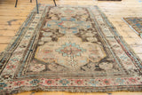 Distressed antique Caucasian rug: close-up of geometric patterns, muted blues, pinks, and worn fringe.