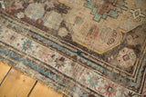 Textured border of antique Caucasian rug, worn geometric patterns in muted blue, pink, brown.