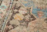 Distressed antique Caucasian rug showcasing low pile texture with sky blue, walnut, pink, and yellow hues.