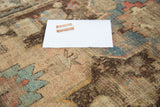 Distressed antique Caucasian rug texture close-up with geometric blue, brown, pink hues.
