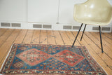 Distressed antique Persian geometric medallion rug in terra cotta and blue hues.