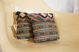 Two Small Kilim pillows with faded antique geometric patterns in earth tones.