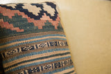 Antique kilim pillow detail: faded blue, rose, and beige stripes with geometric motifs.