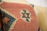 Faded reddish, blue, and tan geometric flatweave on the handmade Kilim pillow.