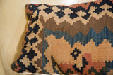 Corner detail of the antique Kilim pillow, showcasing faded tan, blue, and brown geometric motifs.