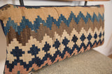 Faded geometric pattern and handwoven flatweave texture of the antique Kilim pillow.