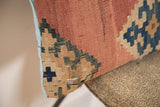 Antique Kilim pillow fragment showing faded rust, blue geometric weave, light blue edge.