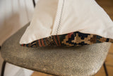 Kilim throw pillow with creamy organic cotton backing and vibrant geometric patterned edge.