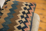 Faded geometric pattern, woven texture, and navy piping on an antique Kilim pillow.