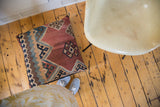 Antique Kilim Floor Pillow showcasing its faded geometric pattern in red, blue, and beige.