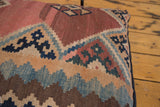 Close-up of circa 1915 Kilim fragment pillow's faded brown, blue, red geometric patterns.