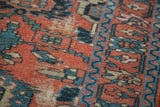 Intricate teal and navy palmettes and serrated leaves on a distressed red Lilihan rug.