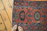 Distressed red Lilihan rug corner with stylized palmettes and teal blue florals.