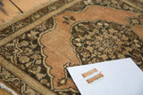 Antique Tabriz rug's scalloped spandrel and leaf motif border in copper, charcoal, and ivory.