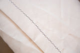 Lumbar pillow's light organic cotton canvas backing with dark zig-zag stitching.