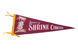 Vintage Shrine Circus souvenir felt pennant in maroon with white graphics of a clown, lion, and tiger.