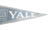 White YALE text on vintage faded blue-gray felt banner, showing texture.